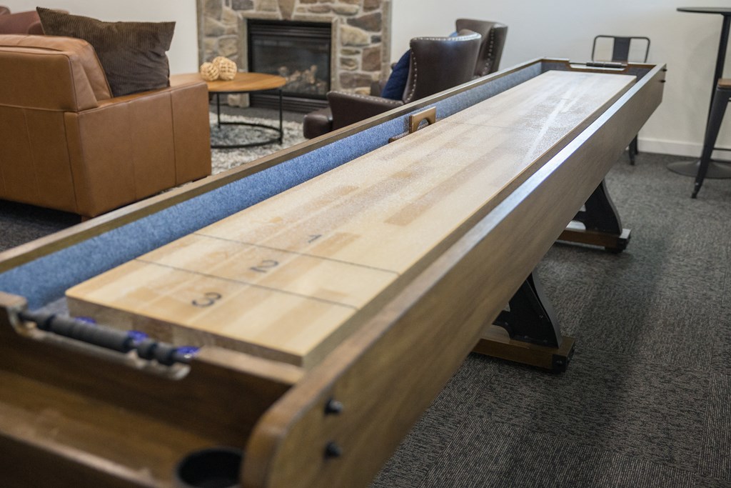 A long wooden table with numbers on it is in the middle of a room with a fireplace and a couch.