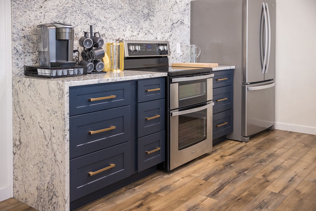 A kitchen with dark blue drawers and a marble countertop.