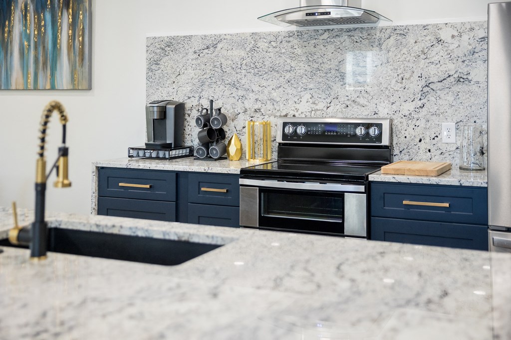 A kitchen with a marble countertop and dark blue drawers.