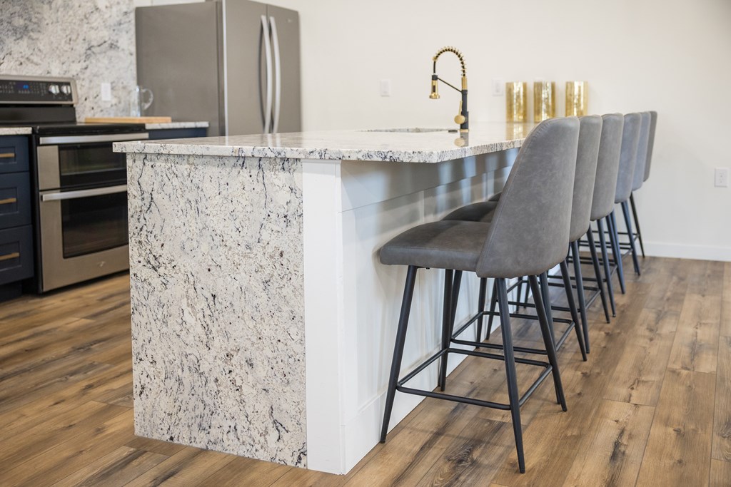 A kitchen with a marble counter and grey bar stools.