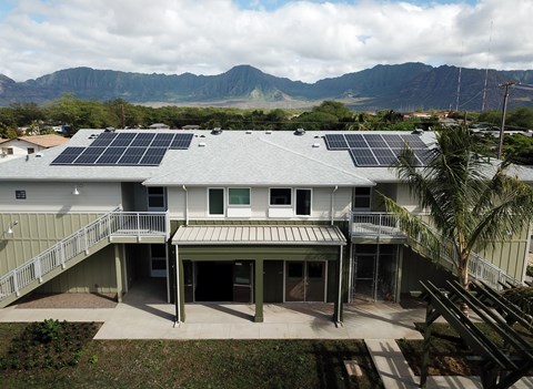 A house with solar panels on the roof and a mountain range in the background.