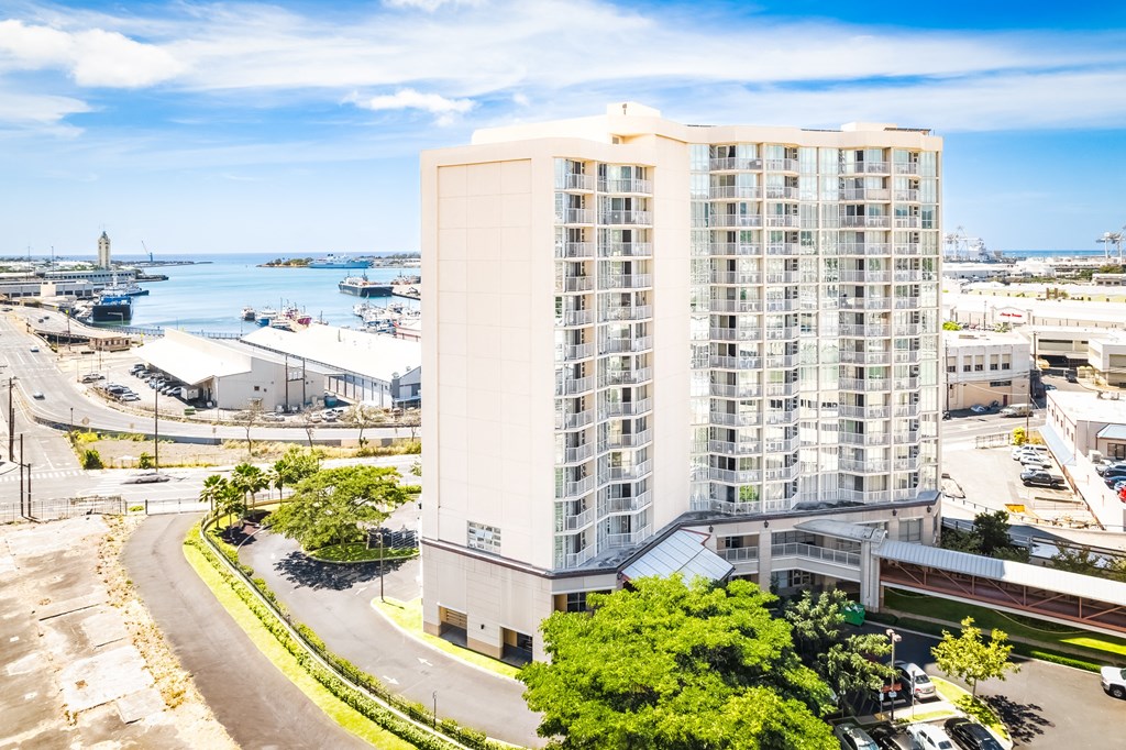 an aerial view of a tall building in a city with a body of water in the background