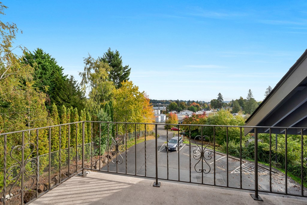 the view from the balcony of a building overlooking a street and trees