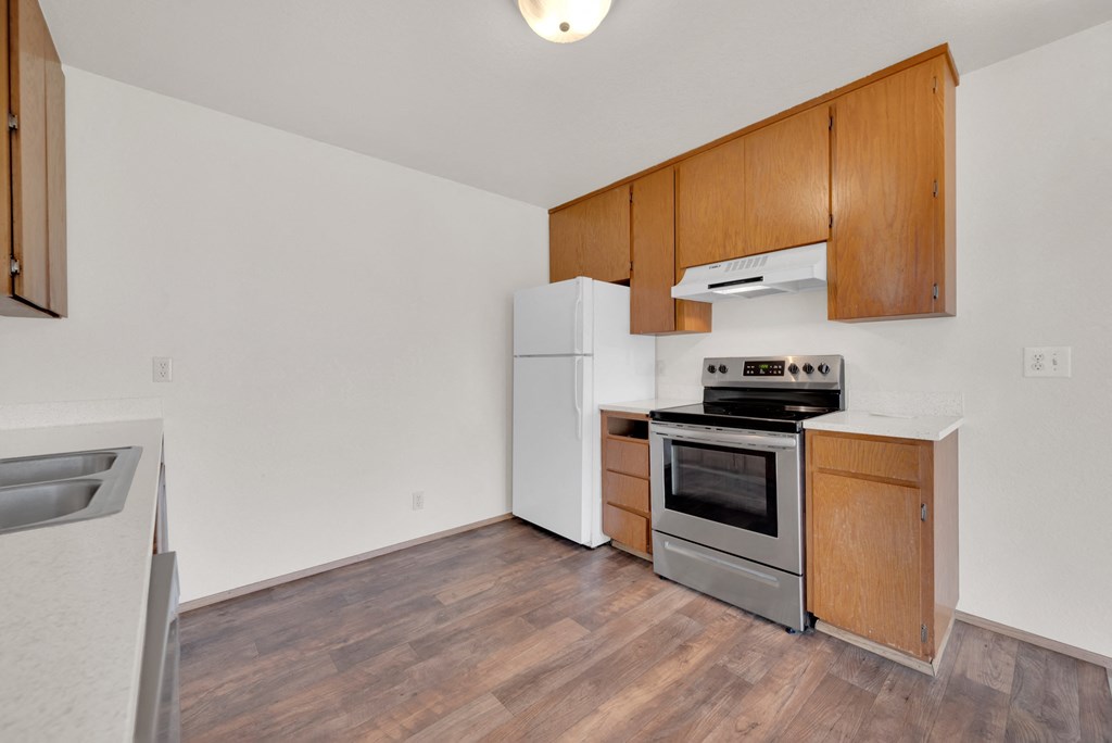 a kitchen with wood flooring and white appliances and wooden cabinets
