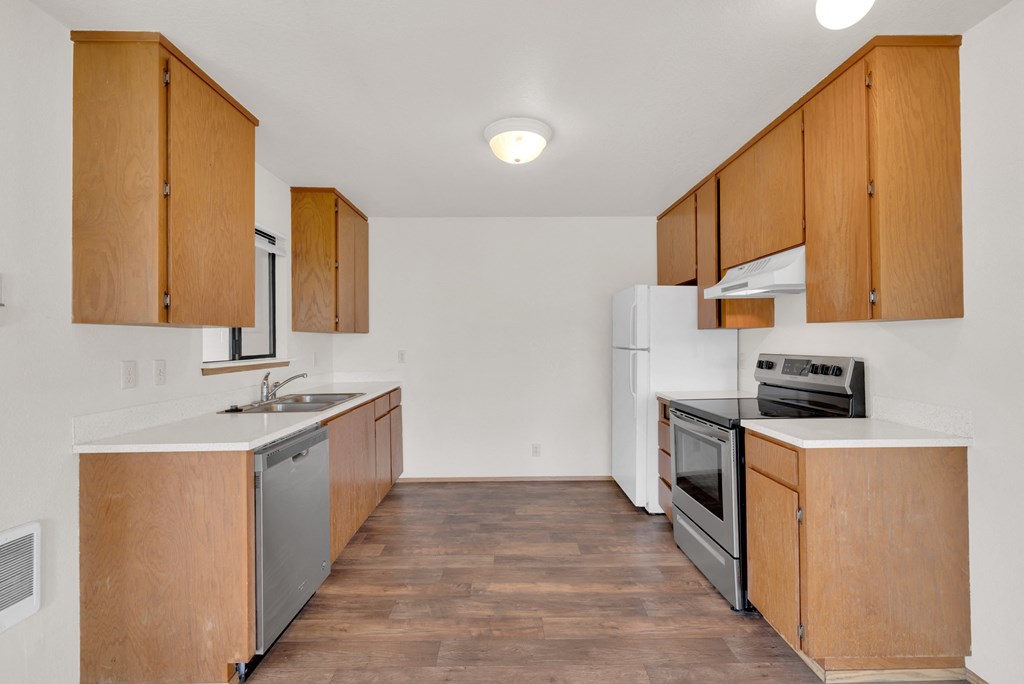 an empty kitchen with wooden cabinets and stainless steel appliances