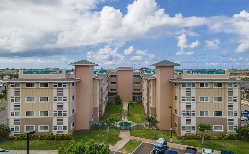 an aerial view of an apartment complex with a blue cloudy sky