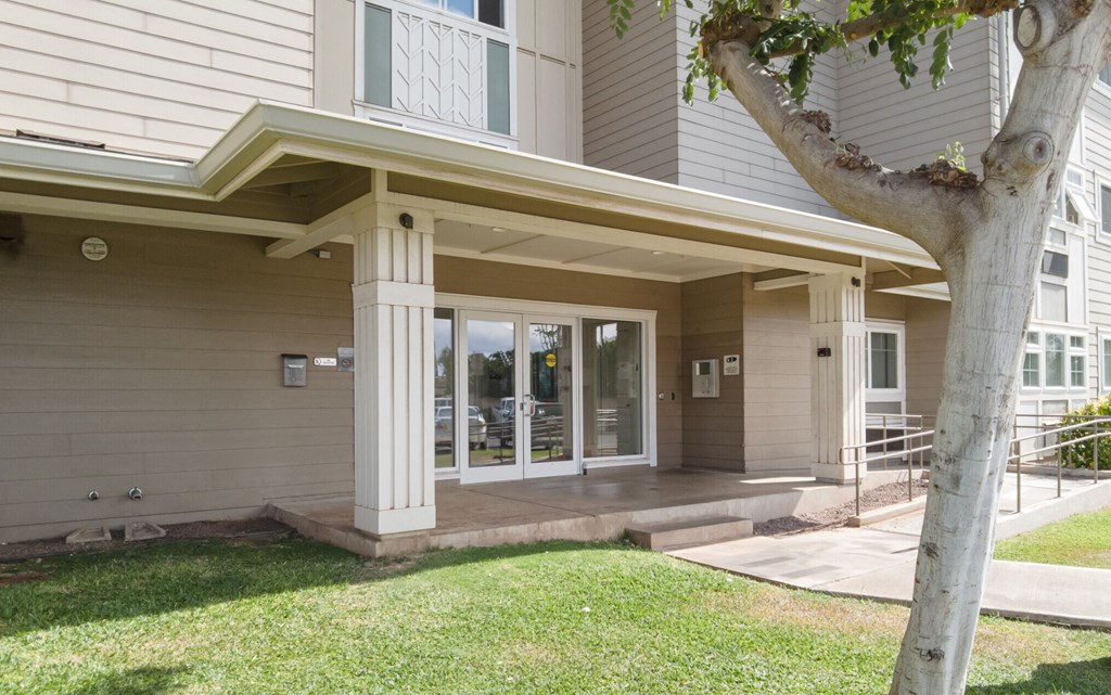 the front of a house with a porch and a tree