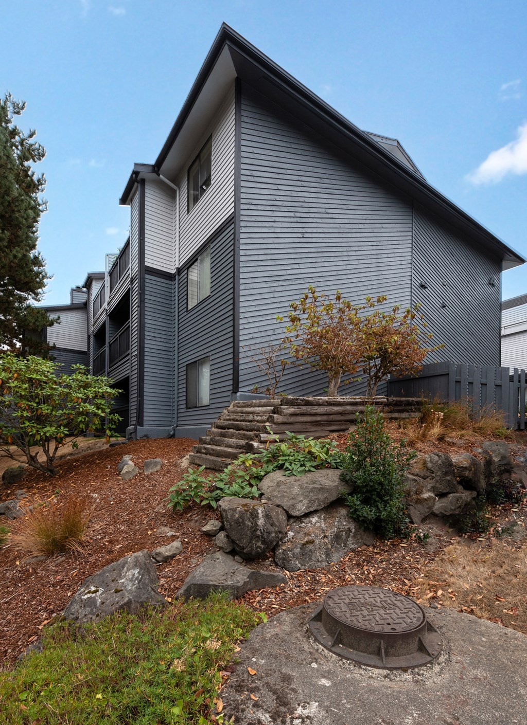 A grey house with a rocky front yard.