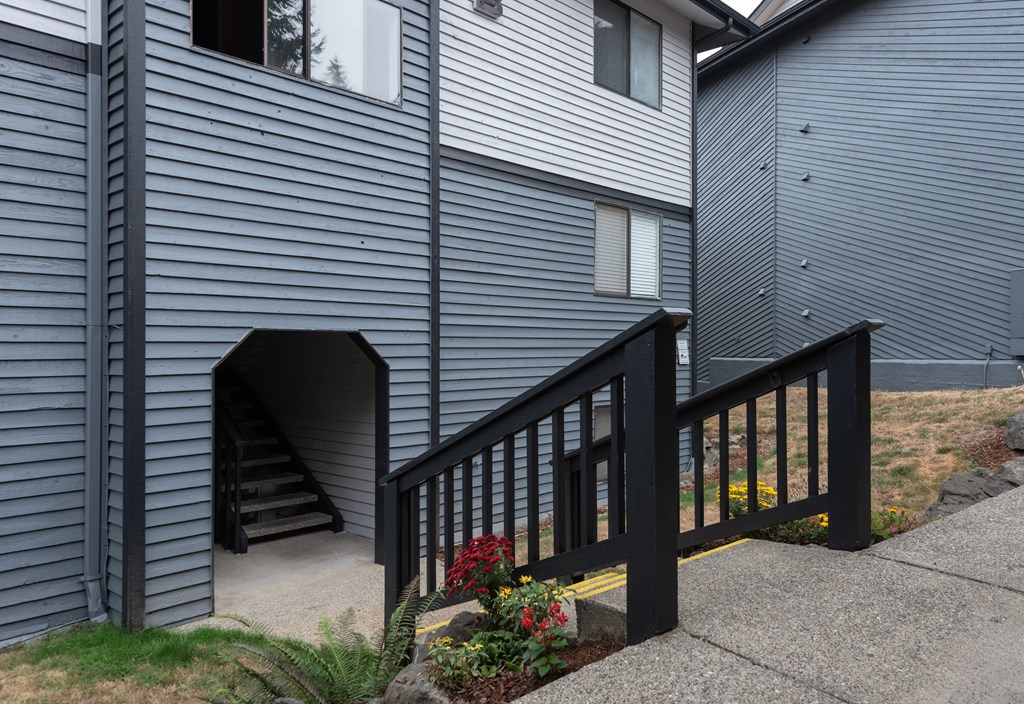 A house with a black railing and a staircase leading to a doorway.