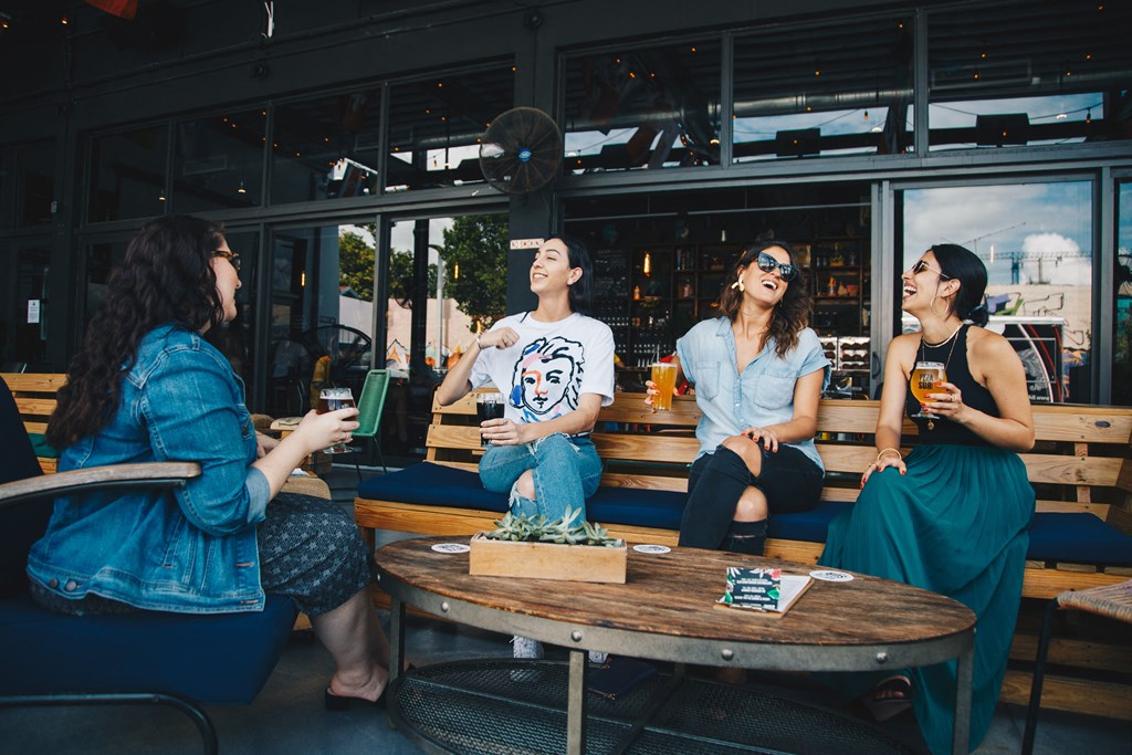 a group of people sitting around a table drinking beer