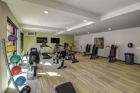 a gym with cardio equipment and weights on a wooden floor