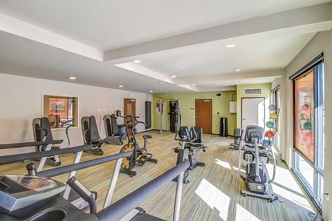 a gym with cardio machines and weights on a wood floor