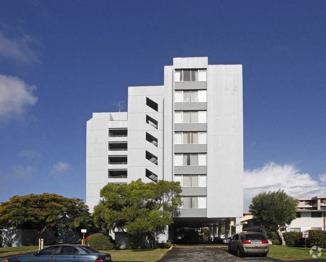 a tall white building with cars parked in front of it