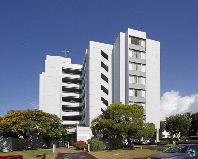 a tall white building with trees in front of it