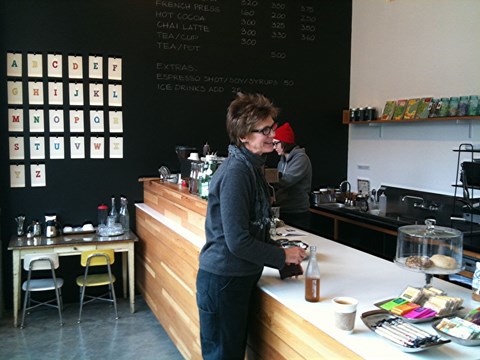 A woman is standing behind a counter in a coffee shop.