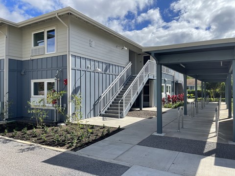A modern building with a grey and blue exterior and a covered walkway.