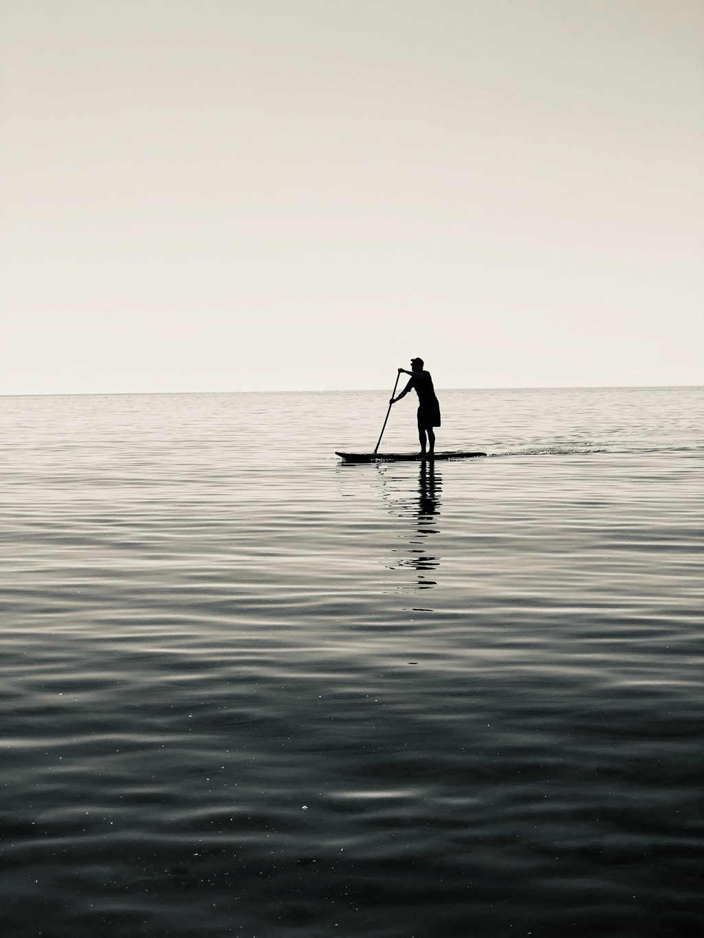 a man standing on a paddle board in the middle of the ocean