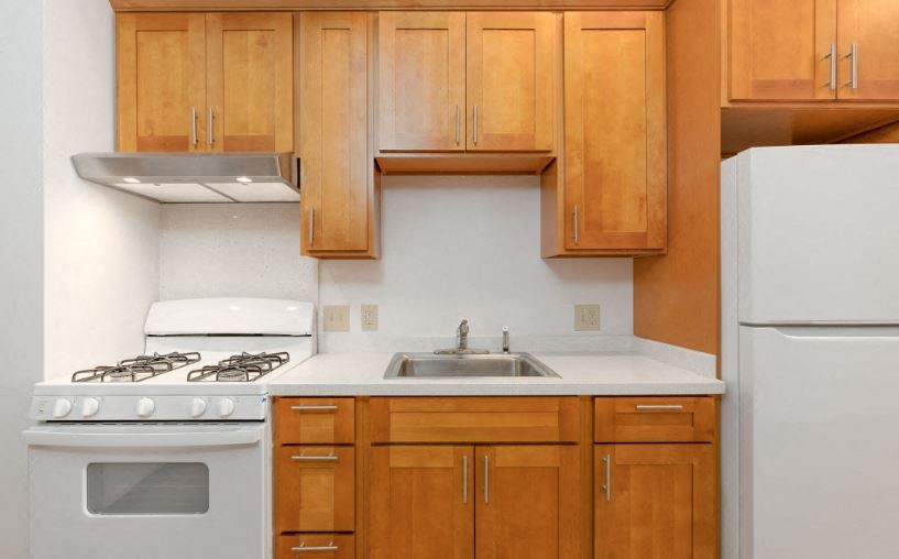 A kitchen with wooden cabinets and a white stove top oven.