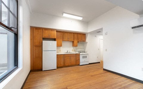 an empty kitchen with white appliances and wooden cabinets