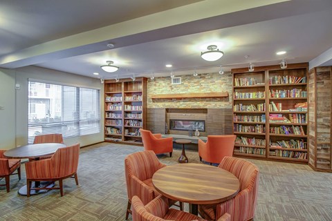 a library with tables and chairs and a fireplace