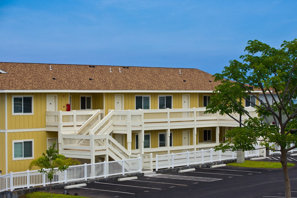 a yellow building with white railings and a brown roof