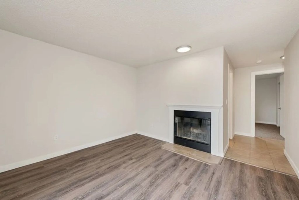 A room with a fireplace and wooden flooring.