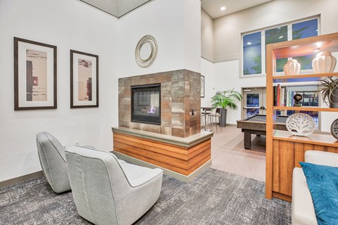 A living room with a grey carpet and a stone fireplace.