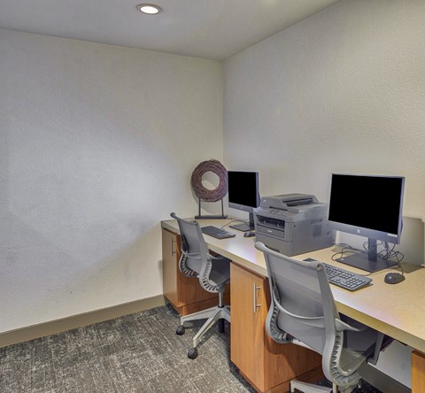 A computer desk with a monitor, keyboard, and printer.