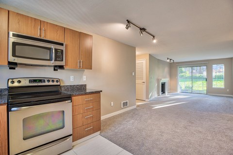 A kitchen with a stove, oven, microwave and cabinets.
