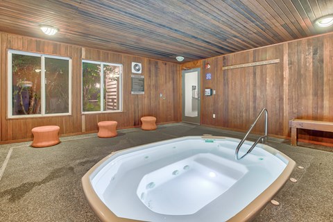 A hot tub is in the middle of a room with wood paneling.