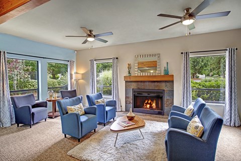 A living room with blue chairs and a fireplace.