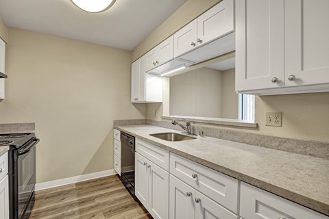 A kitchen with white cabinets and a marble countertop.