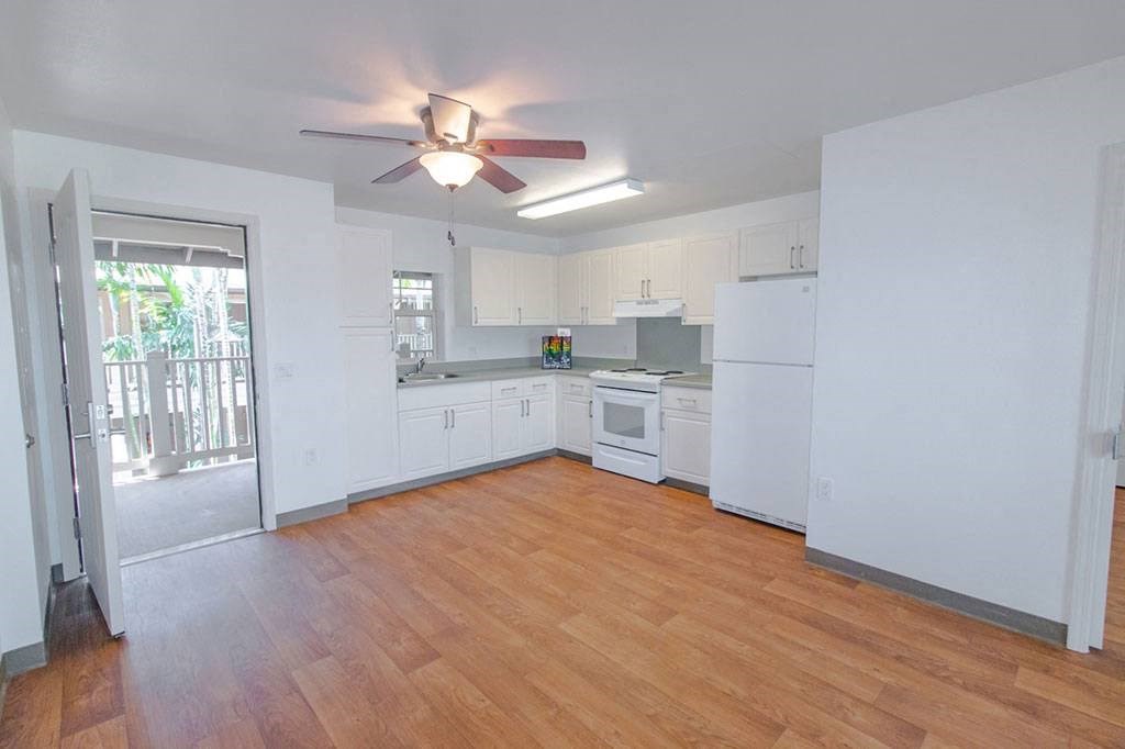 an empty kitchen with white cabinets and a ceiling fan