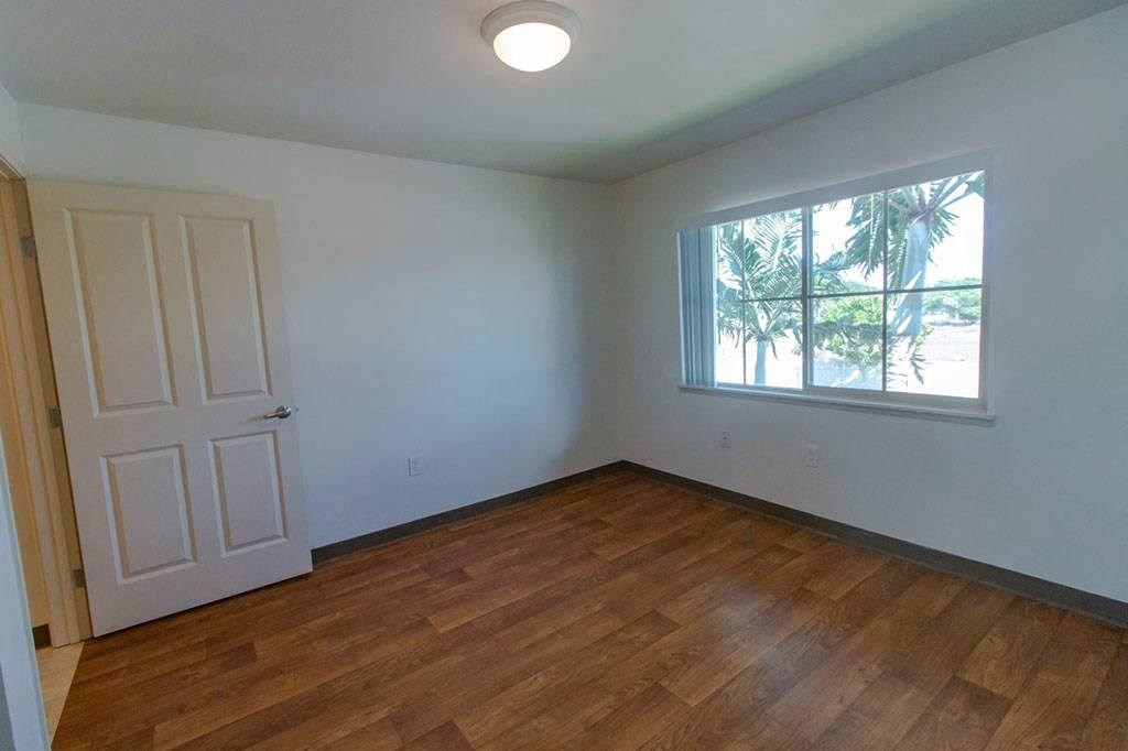 an empty living room with a window and wooden floors