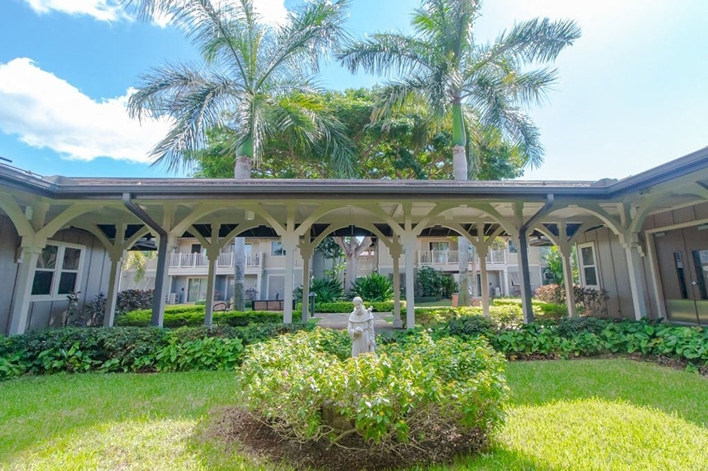 a building with palm trees and a fire hydrant in the grass