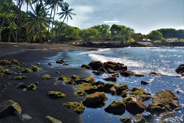 a black sand beach with rocks and water