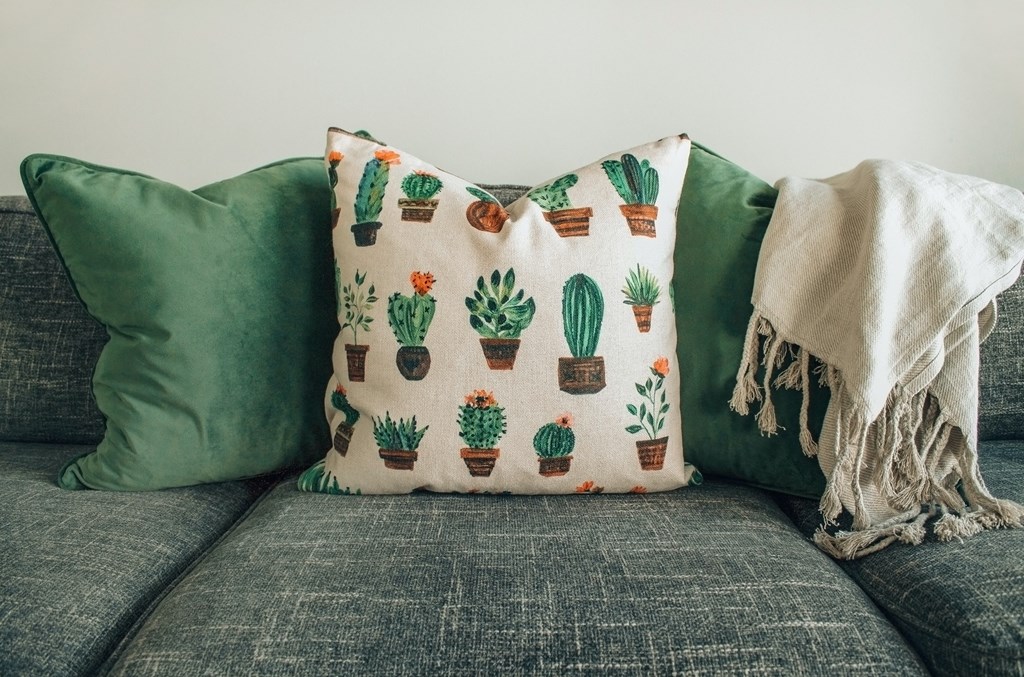 a couch with green pillows and a cactus cushion on it