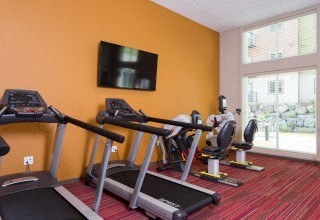 a gym with exercise equipment and a tv on the wall