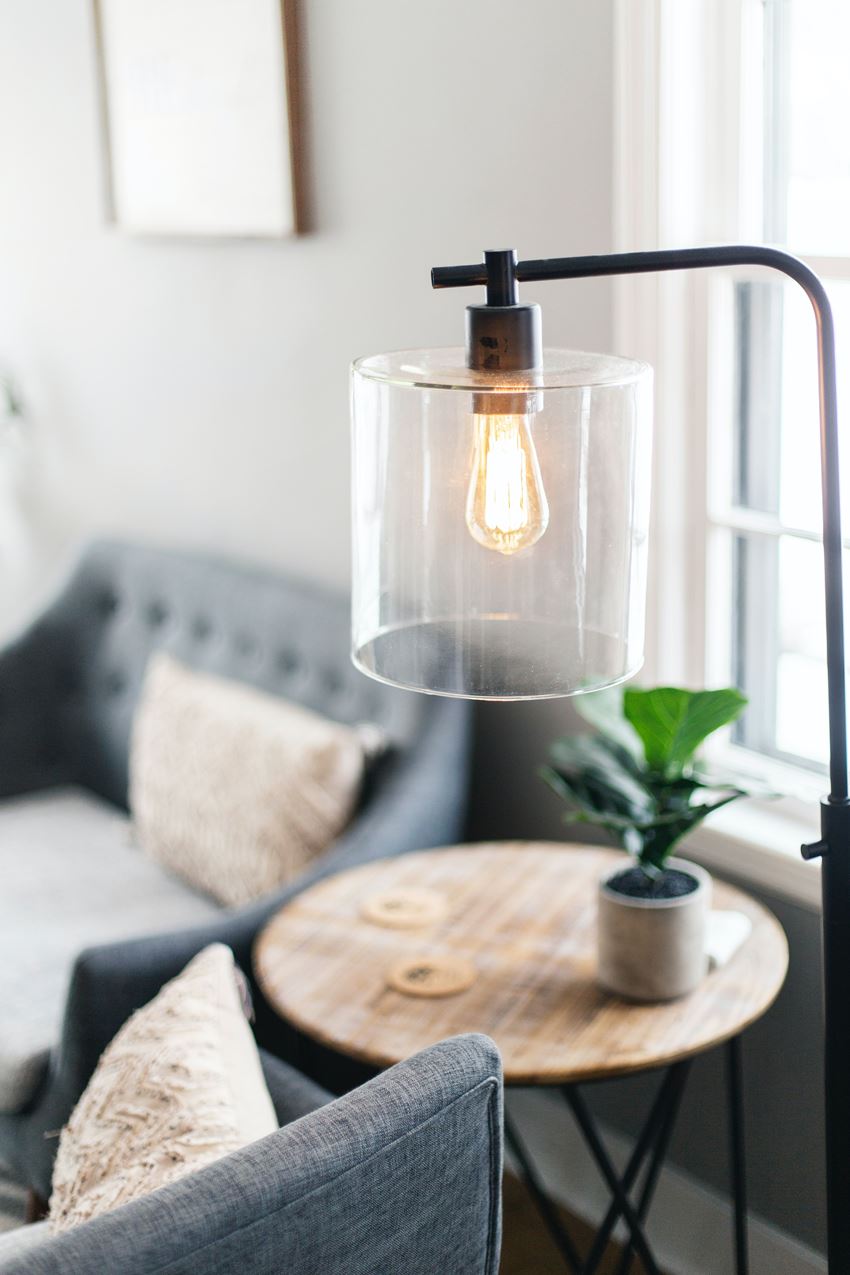 a living room with a couch and a table with a glass lamp