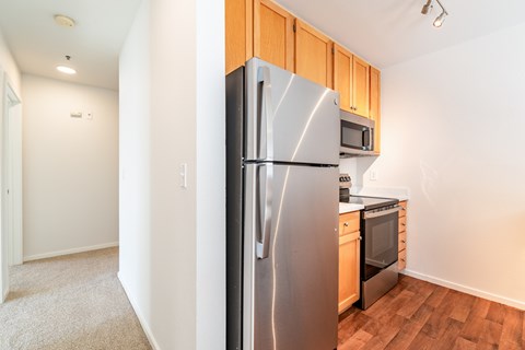 A kitchen with a stainless steel refrigerator and wooden cabinets.