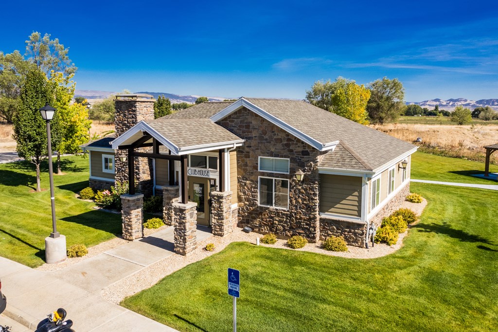 A house with a stone wall and a sign in front.
