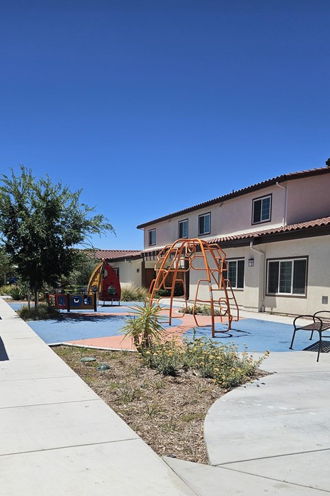 A playground with a swing set and a building in the background.