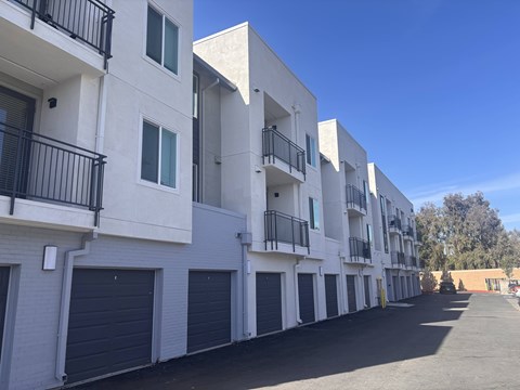 A row of white apartment buildings with black railings and garage doors.