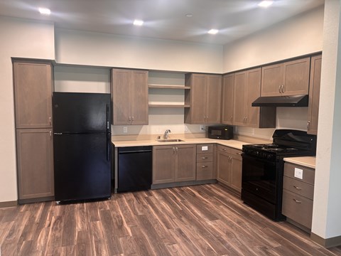 A kitchen with wood flooring and black appliances.