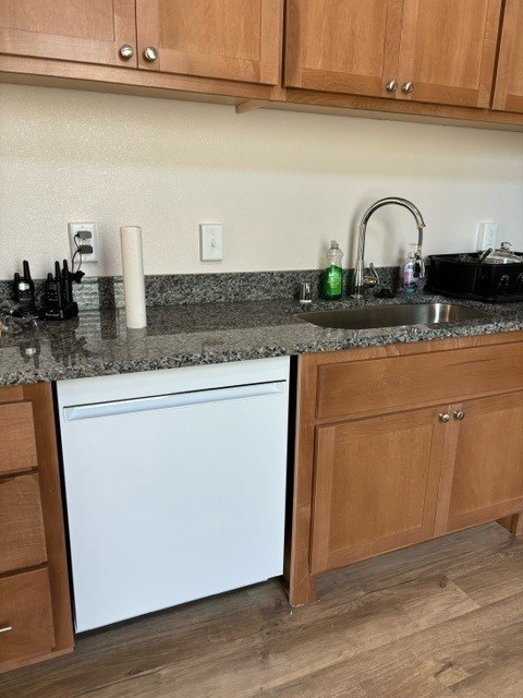 A kitchen with a white dishwasher and wooden cabinets.