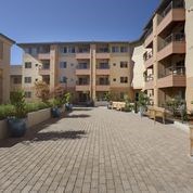 A courtyard with paved ground and apartment buildings in the background.