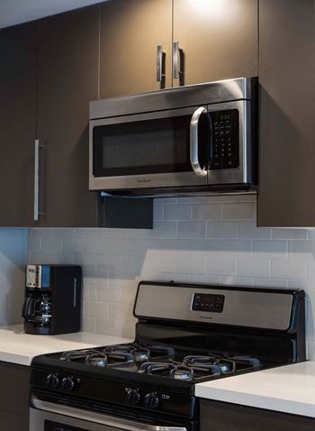 Kitchen with a stove top oven next to a microwave at 888 Hilgard – Furnished Apartments, Los Angeles