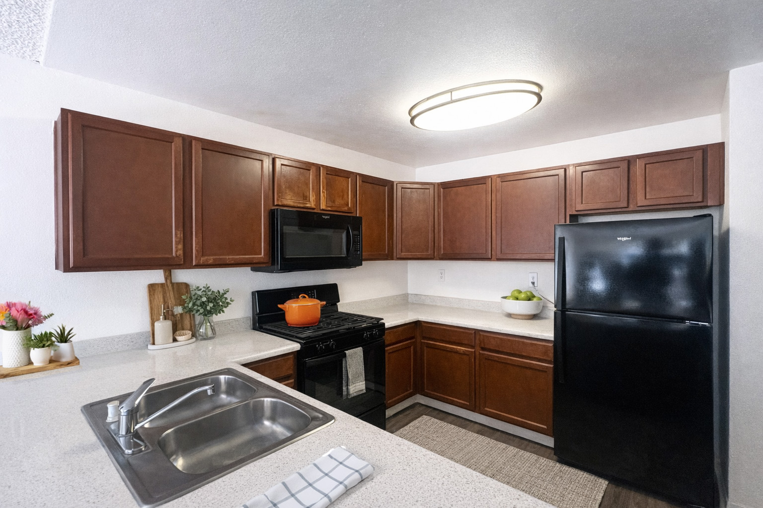 A kitchen with brown cabinets and a black refrigerator.