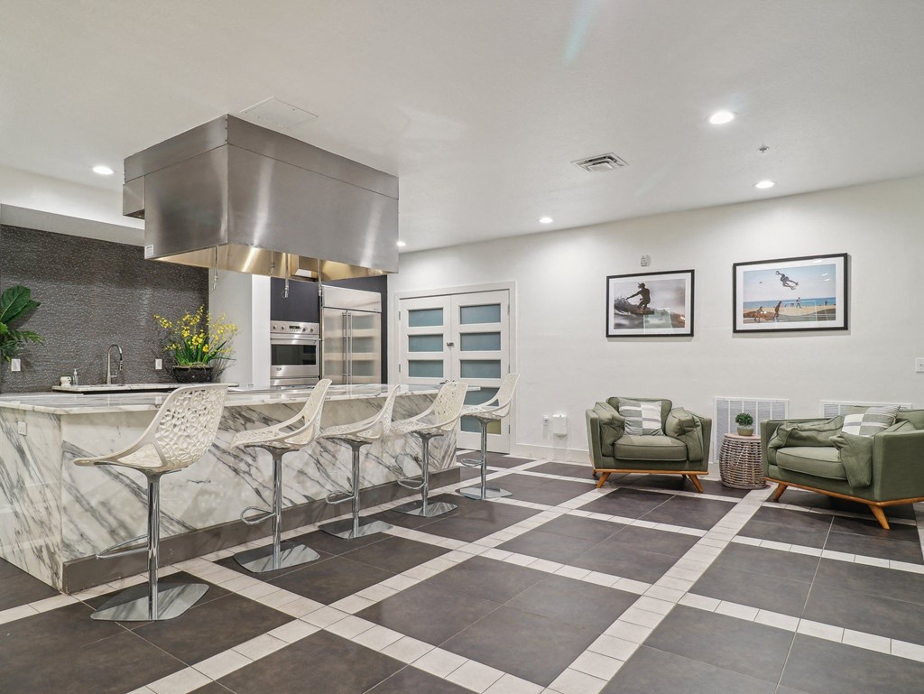 the kitchen has a large island with bar stools and a stainless steel stove top
