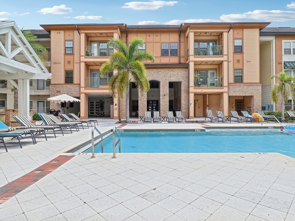 a swimming pool in front of a building with a resort style pool